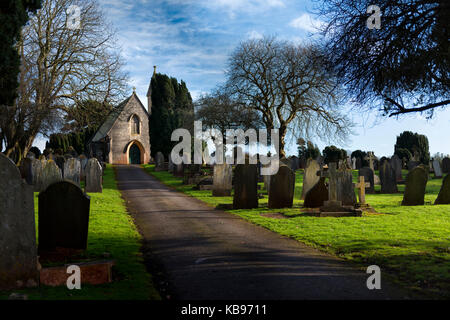Blick auf die anglikanische Kapelle in der Viktorianischen Garten Friedhof, Torquay mit Schlitten Auffahrt durch den Friedhof führt. Winter Sonnenschein Stockfoto