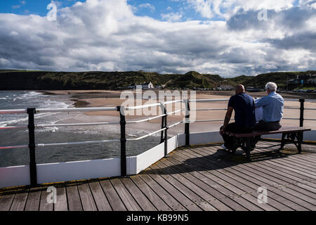 Zwei Männer saßen auf einer Bank auf dem Pier in Saltburn am Meer, England, Großbritannien Stockfoto