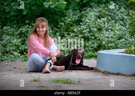 Blonde Mädchen lächelnd mit Hund Labrador. Labrador nebeneinander liegend Stockfoto