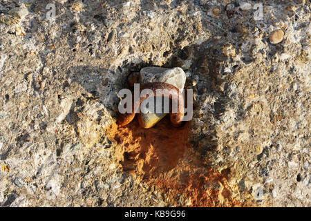 Große konkrete rechteckigen Blöcken am Ufer von Erosion liegen im Meer zu schützen. Gehäuse von Eisenbahnschienen. Rusty Schleife auf dem Betonblock Stockfoto