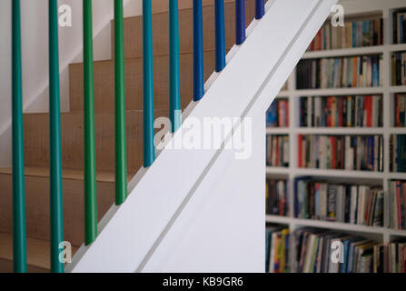 Wohn- Holztreppe mit Spindeln in Grün und Blau ombre Farben gemalt, und Bücherregale im Hintergrund Stockfoto