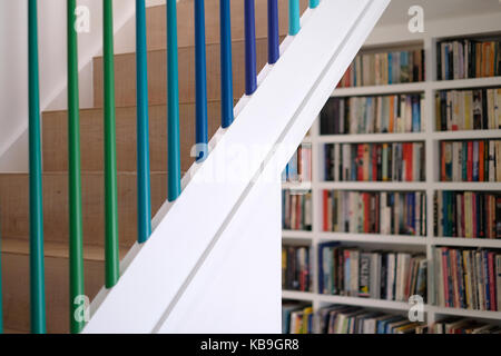 Wohn- Holztreppe mit Spindeln in Grün und Blau ombre Farben gemalt, und Bücherregale im Hintergrund Stockfoto