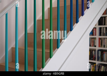 Wohn- Holztreppe mit Spindeln in Grün und Blau ombre Farben gemalt, und Bücherregale im Hintergrund Stockfoto