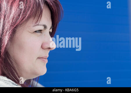 Bildnis eines rothaarigen Frau gegen blaue Wand Stockfoto