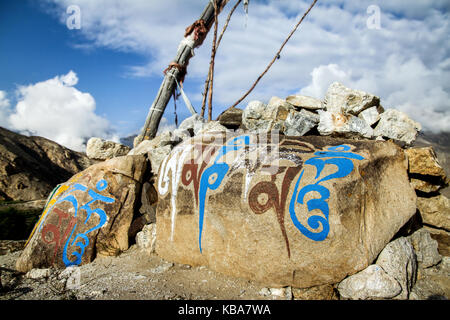 Om Mani Padme Hum heilige Mantra der Buddhisten auf einem Felsen in die Berge des Himalaja in Indien gemalt. heiligen Silben des tibetischen Buddhismus auf blauen Himmel Stockfoto