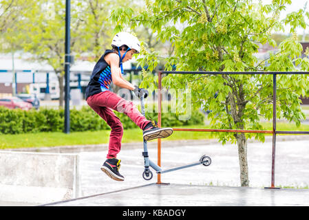 Saguenay, Kanada - Juni 3, 2017: Downtown City Sommer Park in Quebec mit junger Teenager boy Skaten, Durchführung tailwhip Tricks, Stunts auf Scooter auf Stockfoto