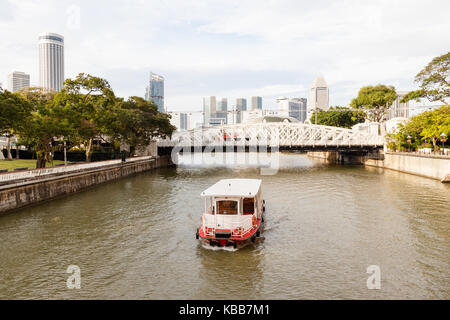 Ein Boot ply auf dem Singapore River Boat Quay in Richtung Anderson Bridge, mit der Skyline der Stadt im Hintergrund. Stockfoto