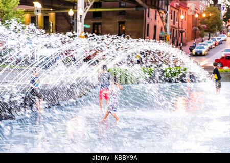 Washington DC, USA - August 4, 2017: Junge jungen Kindern beim Spielen im Brunnen in Georgetown Waterfront Park in den Abend mit Wasser spritzen Stockfoto