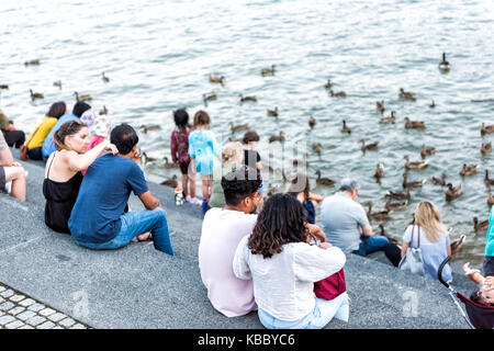 Washington DC, USA - August 4, 2017: die Menschen in Georgetown Waterfront Park am Flussufer in Abend mit Potomac River Fütterung Enten, Gänse Stockfoto