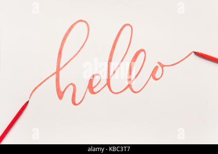 Die grussformel "Hallo" handschriftlich mit orangen Marker auf weißem Papier Stockfoto