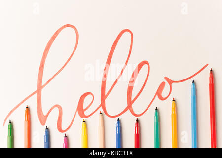 Gruß motivationale bunt Phrase 'Hallo' handschriftlich mit orangen Marker auf weißem Papier. Blick von oben auf die Schriftzüge in Bündel von farbigen Markierungen Stockfoto