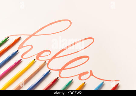 Gruß motivationale bunt Phrase 'Hallo' handschriftlich mit orangen Marker auf weißem Papier. Blick von oben auf die Schriftzüge in Bündel von farbigen Markierungen Stockfoto