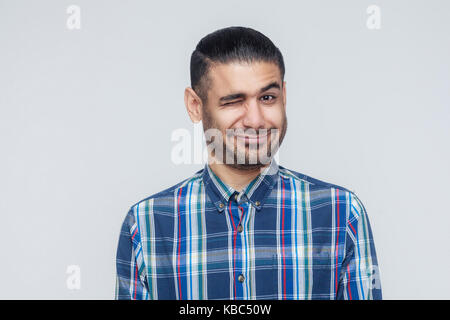 Emotionale hipster Mann Augenzwinkern und Lächeln in die Kamera. Gute Menschen Emotionen und Gefühle. Studio shot, graue Wand Stockfoto