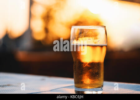 Erfrischende kalte Lagerbier Festlegung auf Tisch gegen Himmel bei Sonnenuntergang Stockfoto