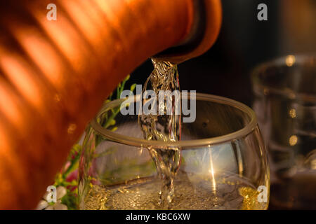 Nahaufnahme der weißen Wein, ausgegossen in Glas Wein bei Sonnenuntergang Stockfoto