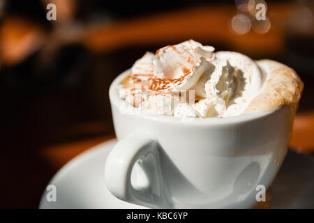 Tasse Cappuccino mit frischer Sahne und Zimt auf der Oberseite Stockfoto