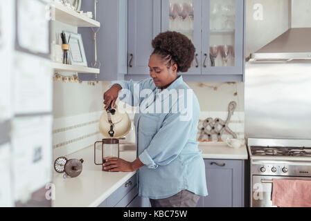 Junge afrikanische Frau vorbereiten frischer Kaffee in Ihrer Küche Stockfoto