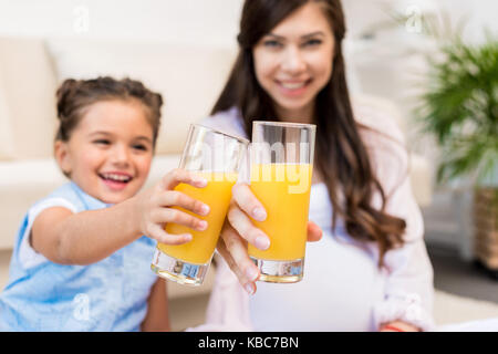 Mädchen und ihre Mutter klirren Gläser Stockfoto