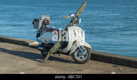 Weiß retro Scooter mit Fanggeräten, stehend auf einem Peer mit blauen Meer im Hintergrund. Hoek van Holland, Niederlande Stockfoto