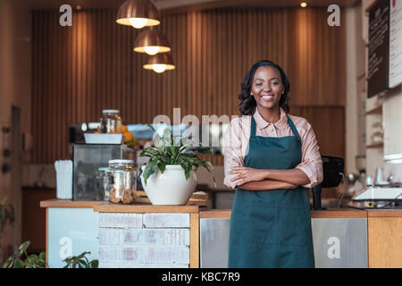 Lächelnden jungen afrikanischen Unternehmer stehen in Ihrem Cafe Stockfoto