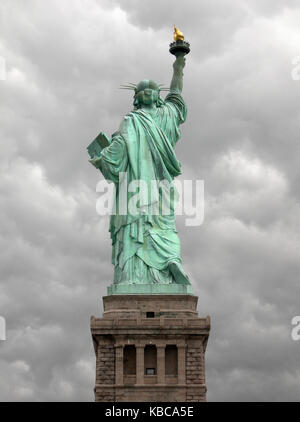 Freiheitsstatue von der Rückseite mit einem grauen und bewölkter Himmel als Hintergrund in Manhattan, New York City gesehen. Stockfoto