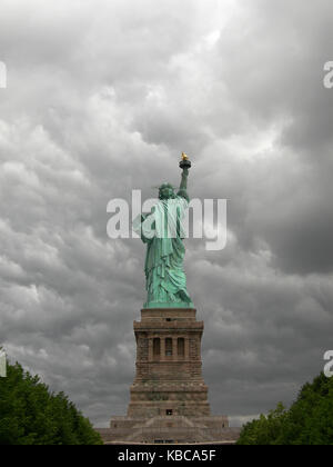 Freiheitsstatue von der Rückseite mit einem grauen und bewölkter Himmel als Hintergrund in Manhattan, New York City gesehen. Stockfoto