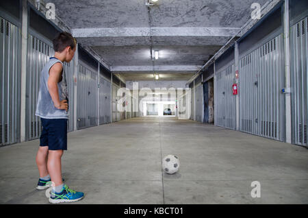 Straße Fußball. Junger Mann Fußball-Spieler. Einsame Training in der Garage. Schwarz-weiss Bild. Stockfoto