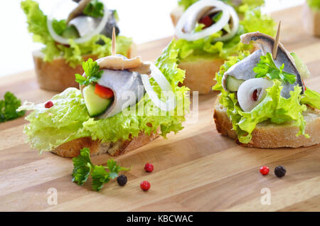 Gebeiztes Heringe auf Scheiben Baguette mit Salat und Zwiebeln Stockfoto