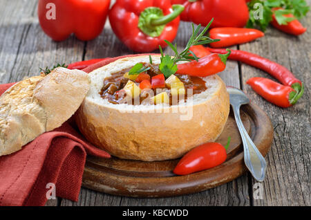 Traditionelle warme ungarische Gulaschsuppe in einem weißen Brotlaib Stockfoto