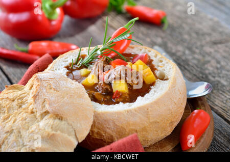 Traditionelle warme ungarische Gulaschsuppe in einem weißen Brotlaib Stockfoto