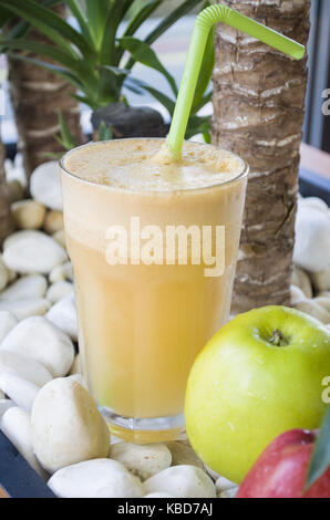 Glas Apfelsaft und grüne Äpfel am weißen Stein Hintergrund Stockfoto