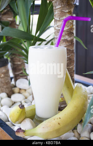 Bananen Smoothie in einem Glas ist am weißen Stein Hintergrund platziert Stockfoto
