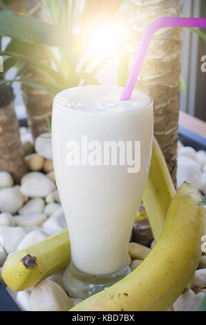 Bananen Smoothie in einem Glas ist am weißen Stein Hintergrund platziert Stockfoto