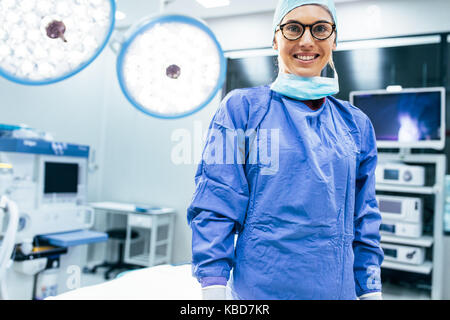 Portrait von lächelnd weibliche Chirurg in chirurgischen einheitliche im Operationssaal. Junge Frau Doktor im Krankenhaus operation Theater. Stockfoto