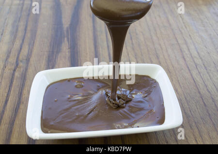Geschmolzene Schokolade auf hölzernen Tisch Stockfoto