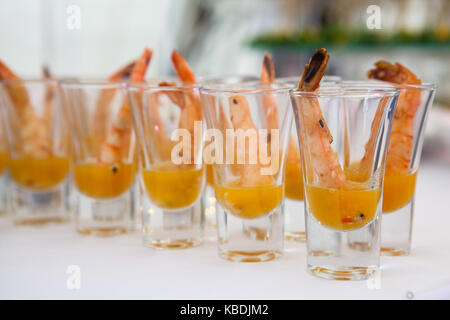 Einzelne Cocktail Shrimps Shot Gläser mit köstlichen hausgemachten Zahnstein pikanter Sauce für Weihnachten Abendessen oder einen Cocktail Party, bokeh Hintergrund, Nahaufnahme, selektiven Fokus Stockfoto