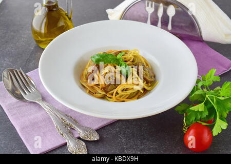 Pasta mit Pilzen und Pesto in eine weiße Platte auf abstrakten Hintergrund. Italienische Lebensart. Gesunde Ernährung Konzept Stockfoto