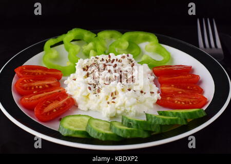 Einfaches Frühstück mit Paprika, Tomaten, Gurken mit Quark und Leinsamen auf einem Schild auf einem dunklen Hintergrund Gesunde Ernährung Konzept. Gesunde Ernährung Stockfoto