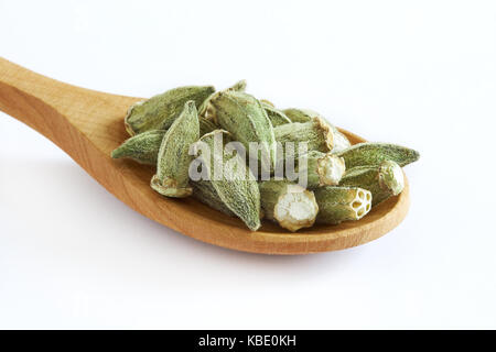 Getrockneten Okra (finger Damen, ochro) Löffel aus Holz auf weißem Hintergrund Stockfoto