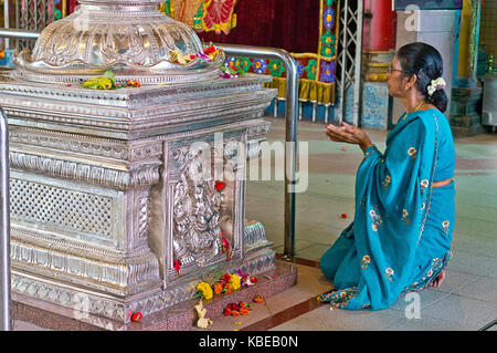 Die Verehrung einer Frau im Sri Srinivasa Perumal Tempel, einem der ältesten Hindu-Tempel Singapurs, im Herzen von Little India, wo der große Gopuram zu sehen ist Stockfoto