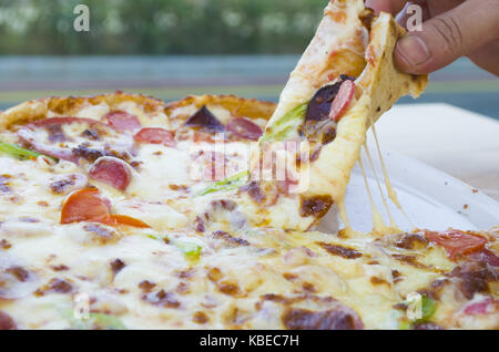 Ein Stück Pizza in der Hand ein Restaurant schönen Hintergrund Stockfoto