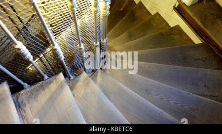 Eine hölzerne Treppe mit Metallschienen Spirale nach unten Stockfoto