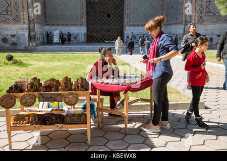 SAMARKAND, Usbekistan - Oktober 15, 2016: Unbekannter touristische Frau Souvenirs kauft in der Bibi-Khanum Moschee von einem lokalen weiblichen Verkäuferin Stockfoto