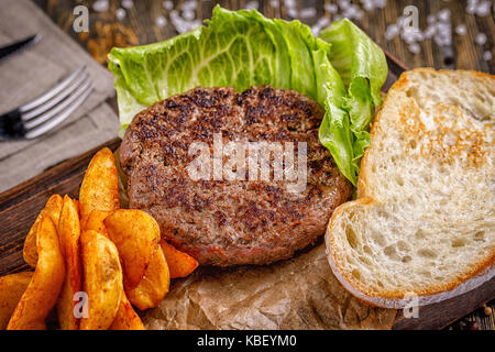 Fast Food Restaurant. Eine gut gebratene leckeres Schnitzel mit goldenen knusprigen Pommes Frites, ein Salatblatt und gerösteten knusprigen Toast. Stockfoto