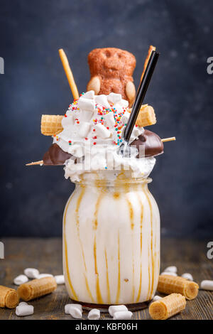 Ungewöhnliche Milchshake mit Bonbons, Marshmallows, Schlagsahne und andere Süßigkeiten eingerichtet. Stockfoto