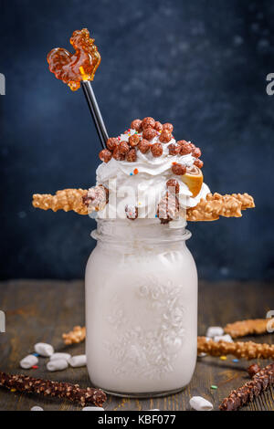 Ungewöhnliche Milchshake mit Bonbons, Marshmallows, Schlagsahne und andere Süßigkeiten eingerichtet. Stockfoto