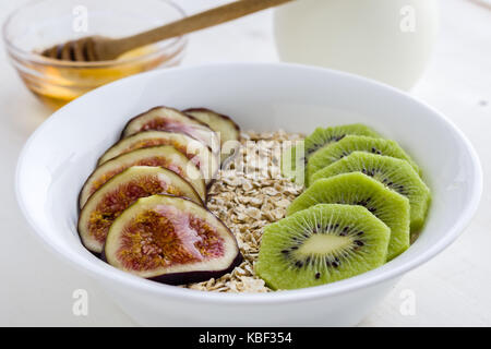 Feigen und Kiwi Müsli mit Honig in weiße Schüssel Stockfoto