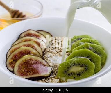 Feigen und Kiwi Müsli mit Honig in weiße Schüssel Stockfoto