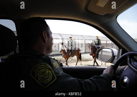 San Diego, USA. 29 Sep, 2017. US Border Patrol-Agenten Saul Rocha, Links, stoppt Hallo Kollegen Grenze Patrouille Offiziere auf dem Rücken der Pferde in der Nähe des sekundären Grenzzaun zu Mexiko zu sagen. Beiden Vertragspartnern der Regierung begann mit dem Bau von Prototypen der vorgeschlagenen Grenzmauer Präsident Donald Trump mit Mexiko in dieser Woche, acht Modelle werden schließlich in einer abgelegenen Gegend von San Diego östlich der Otay Mesa Grenzübergang errichtet werden. Zoll- und Grenzschutz kann mehrere Gewinner oder Keine auswählen. Credit: ZUMA Press, Inc./Alamy leben Nachrichten Stockfoto