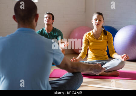 Yoga Lehrer führen Schüler in der Meditation im Health Club Stockfoto